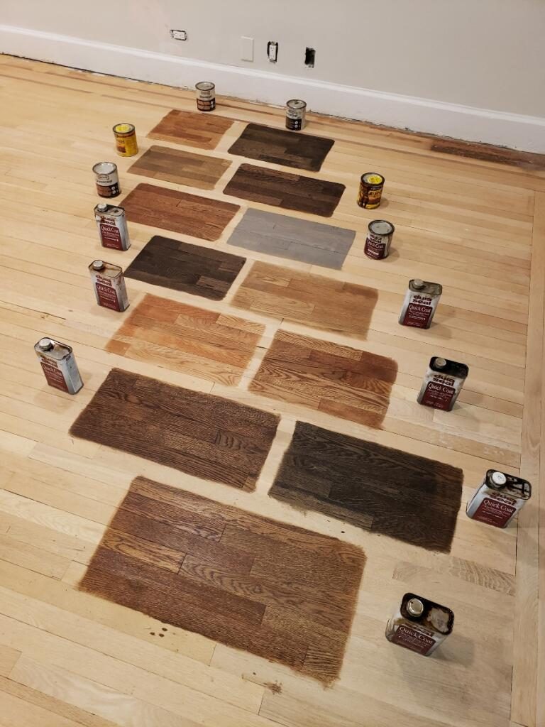 Stain color samples laid out on a sanded hardwood floor with Duraseal and Minwax cans