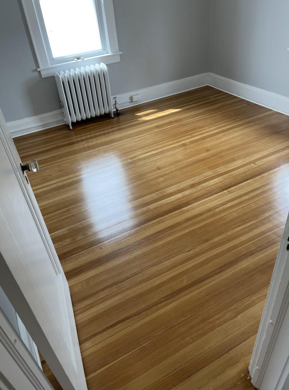 Refinished hardwood floor in a bedroom with a radiator