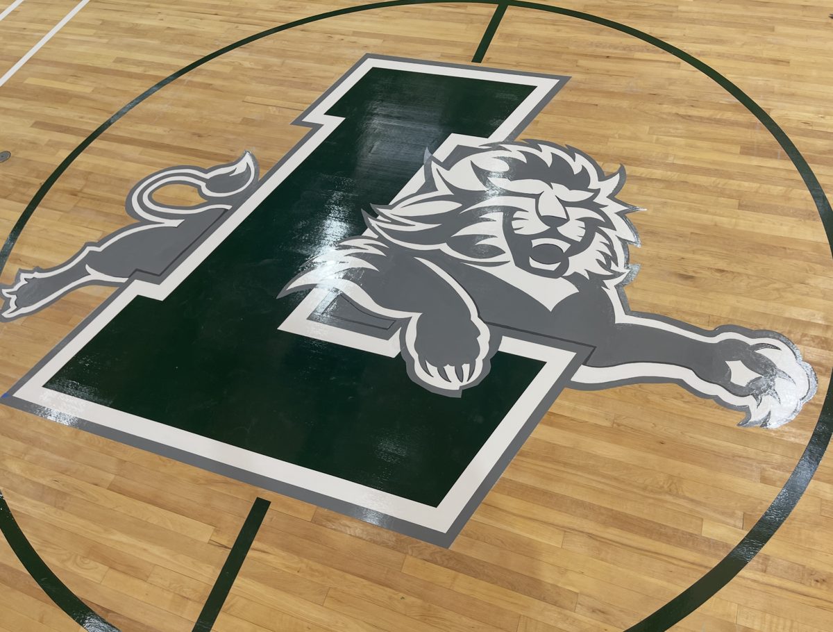 Finished gym floor with a green and gray lion L logo painted at center court