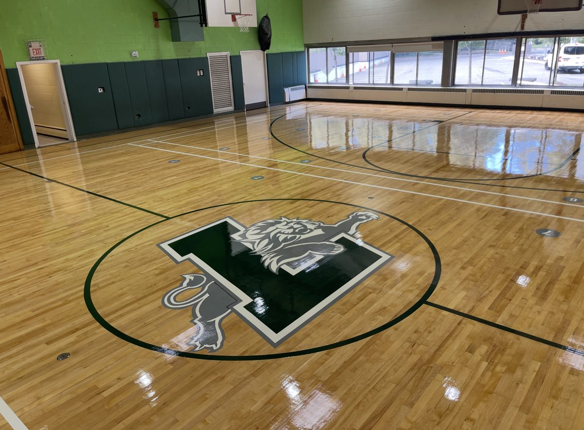 Finished gym floor with a large green and gray lion L logo at center court
