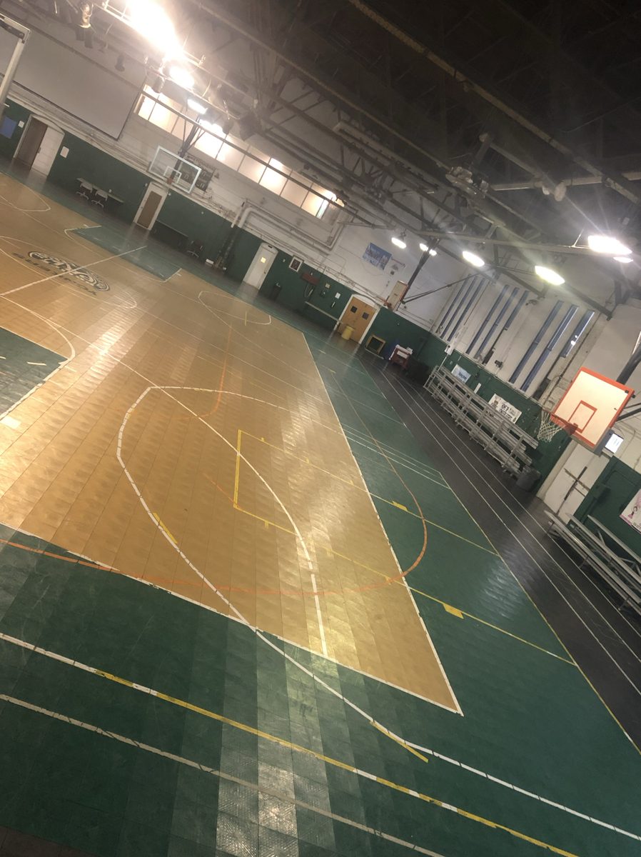 Wide view of the old green and tan interlocking tile basketball court