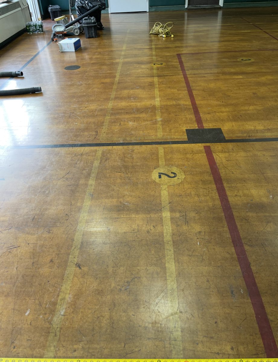 Old scratched and worn gym floor with court lines before refinishing