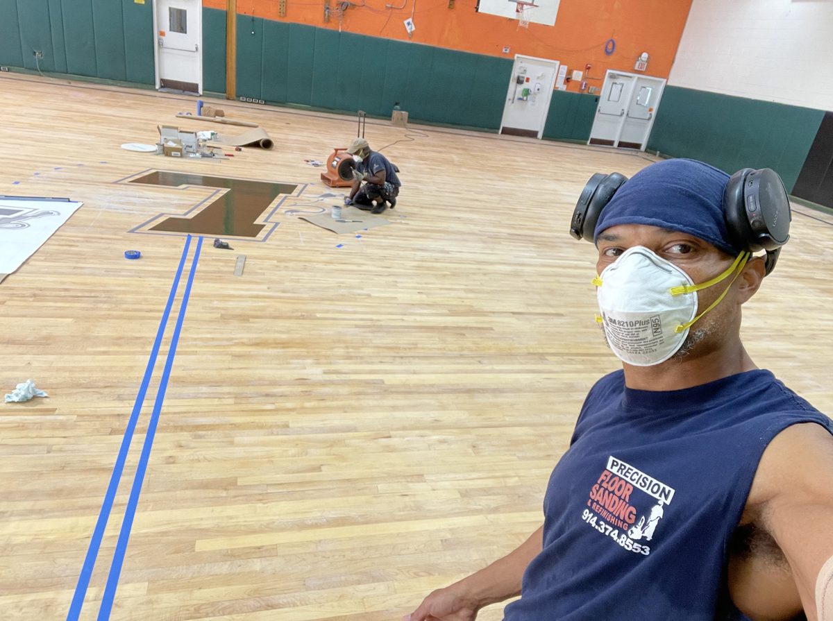 Kwazi wearing a mask and ear protection in the gym while the lion L logo is being painted