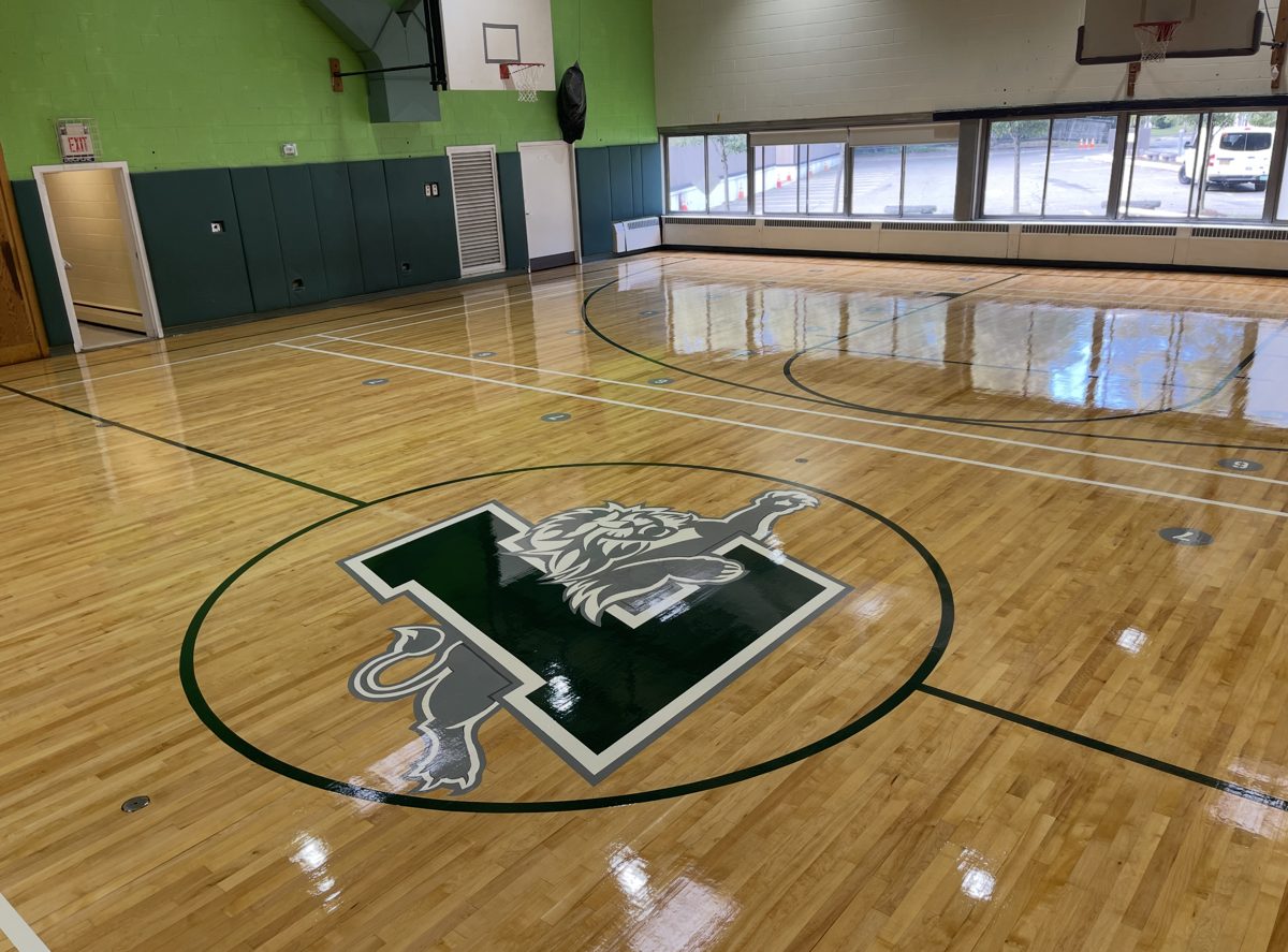 Finished glossy gym floor with a lion and L logo at center court