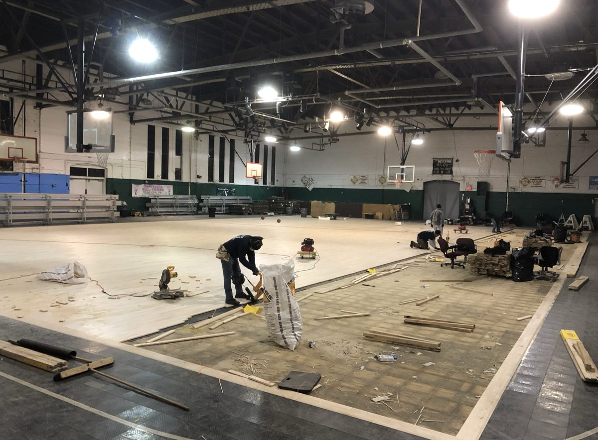 Crew nailing new hardwood next to the remaining old subfloor