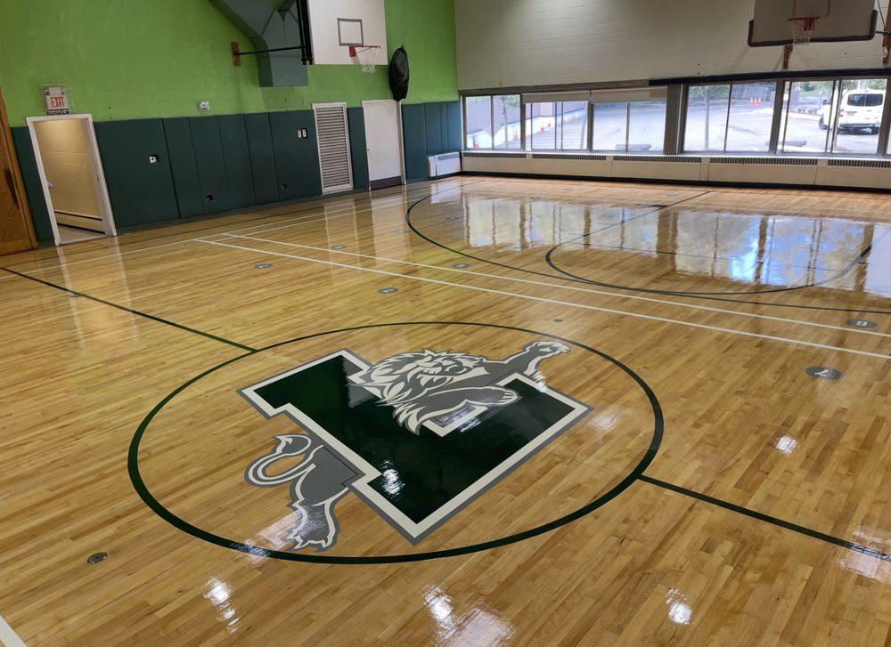 Finished gymnasium floor with a large lion logo at center court
