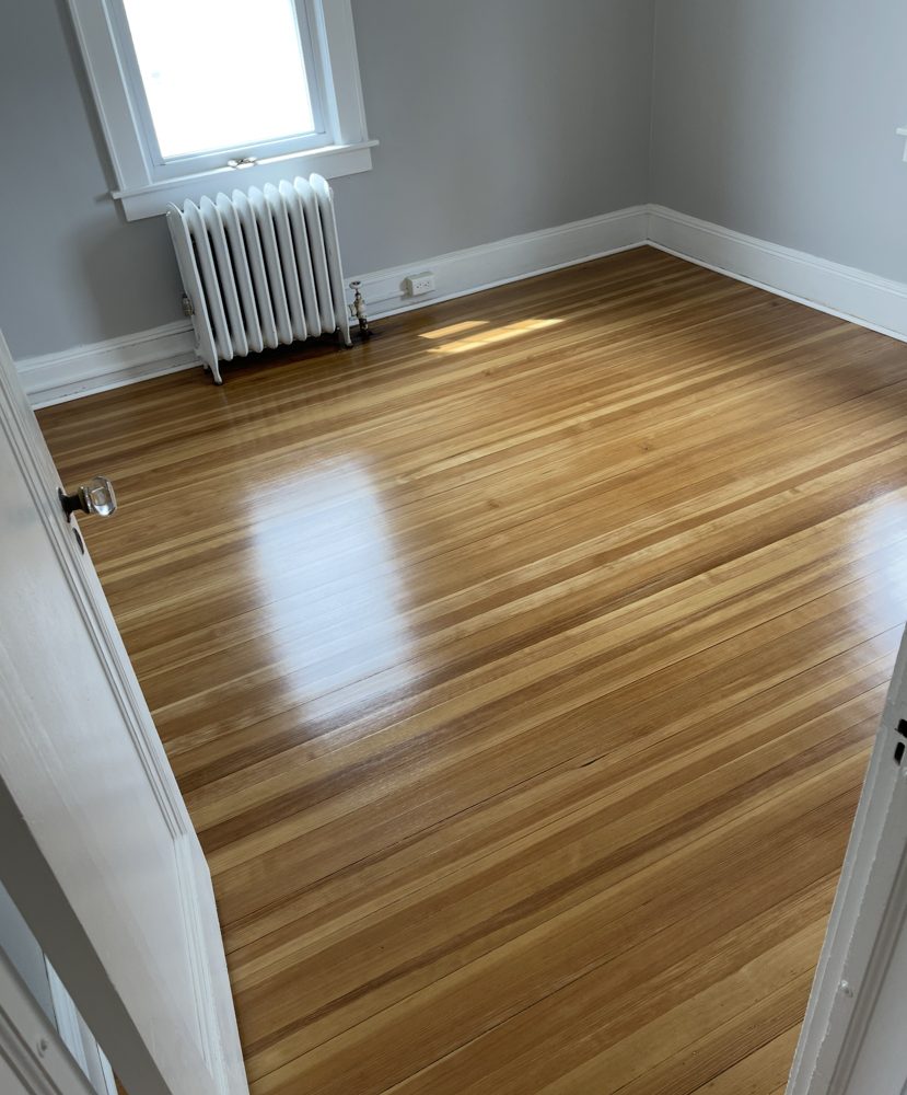 Finished hardwood floor in a bedroom with a radiator