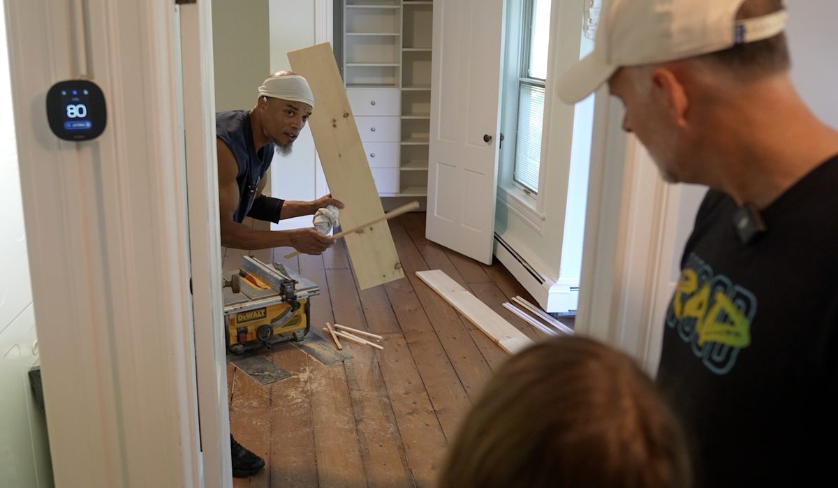 Kwazi cutting new boards on a table saw in a room with old plank flooring
