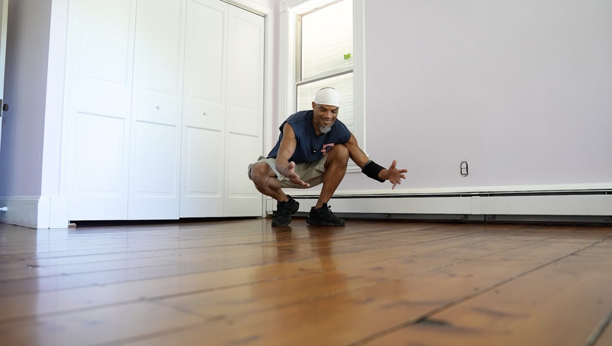 Kwazi crouching to show a repaired plank floor in a finished room